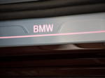 BMW 750Li (G12 LCI) in Royal Burgundy Red Brillianteffekt, Einstiegsleiste mit BMW Schriftzug.