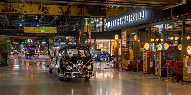 MotorWorld Mnchen, hauseigener VW Transporter, rechts: historische Zapfsulen, restauriert, zum Verkauf