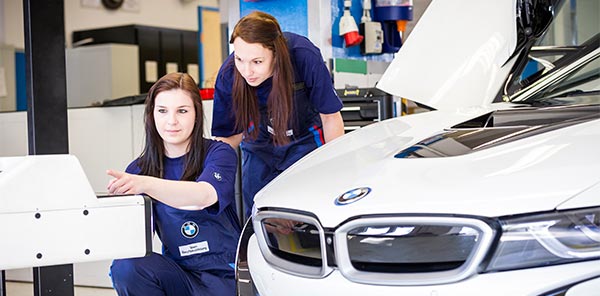 Zwei Auszubildende arbeiten an einem BMW i8.