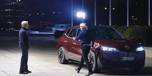 Der BMW Weihnachtsfilm mit Starbesetzung: Christoph Waltz mit dem BMW iX und BMW Chef Olver Zipse vor der BMW Konzernzentrale.